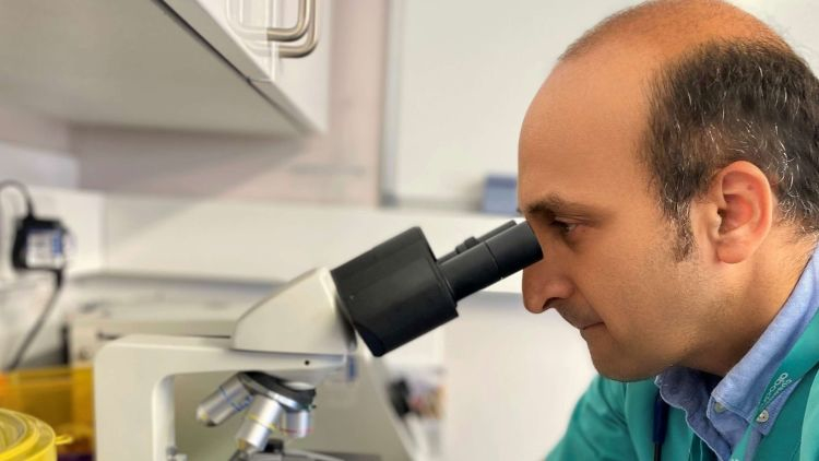 Peter Kukadia examining dermatology samples under a microscope